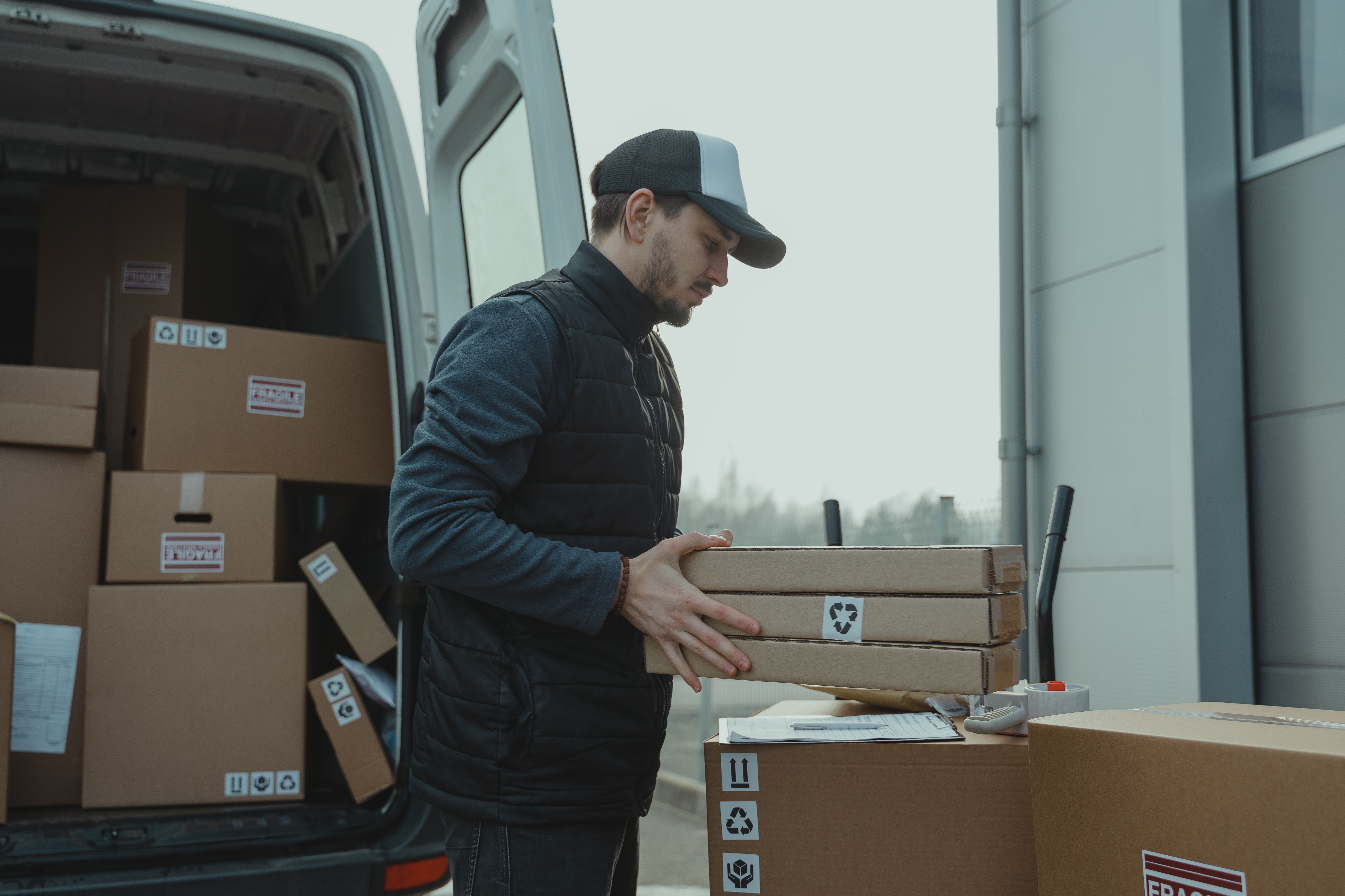 Courier loading parcels into a delivery van at a depot